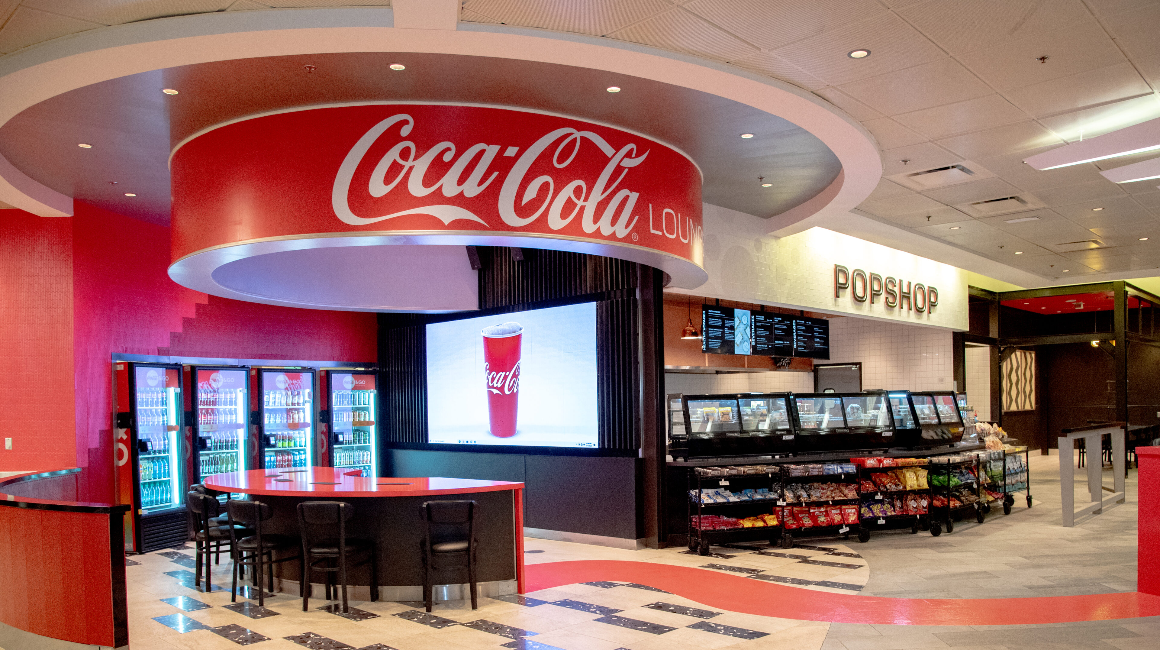 A coca-cola store with a large screen tv.